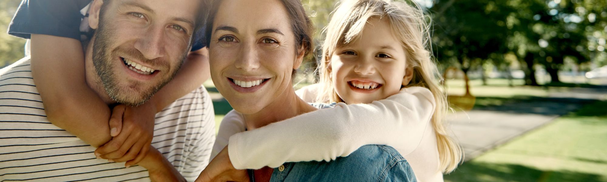 Una familia sonriente, abrazada al aire libre