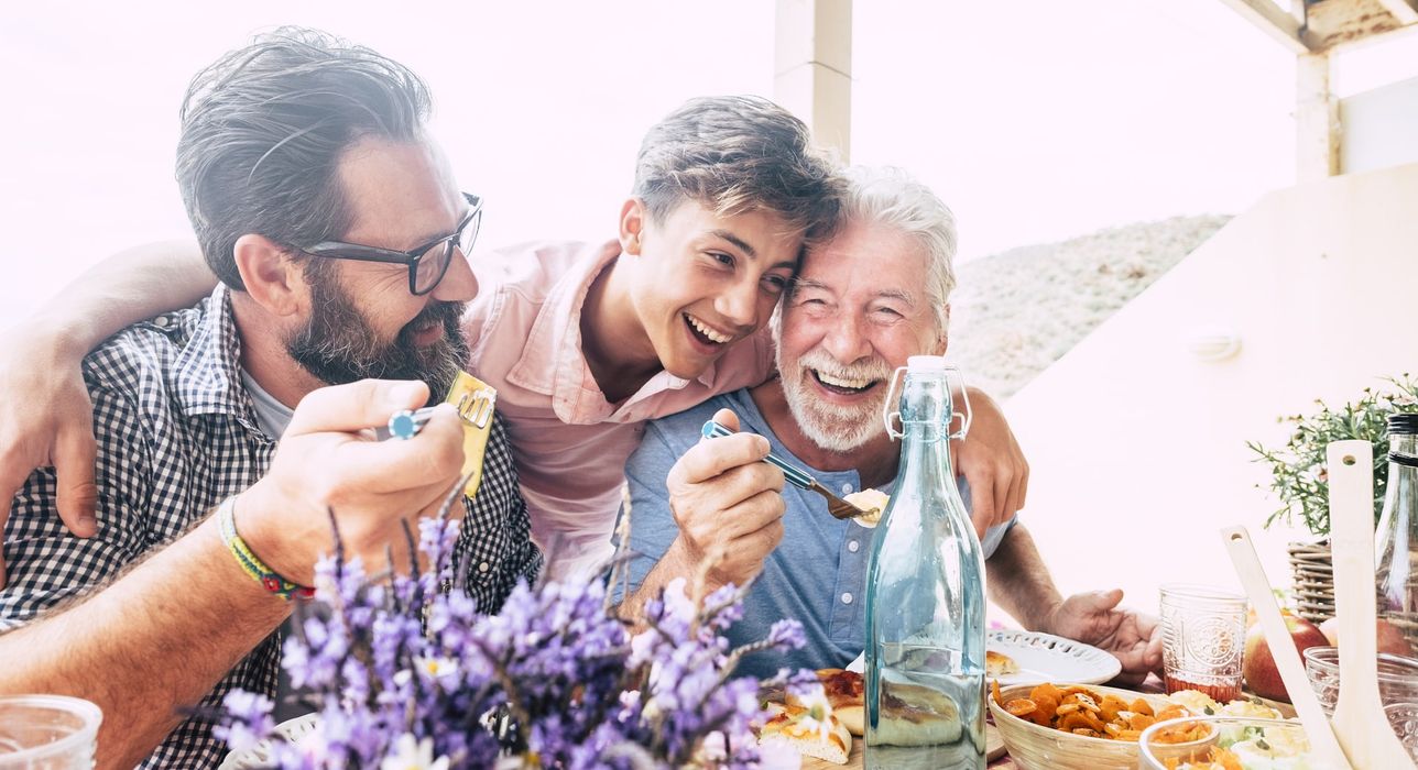 Tres generaciones de una familia ríen durante una comida al aire libre