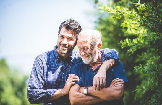 Un hombre abraza a su padre, los dos sonriendo